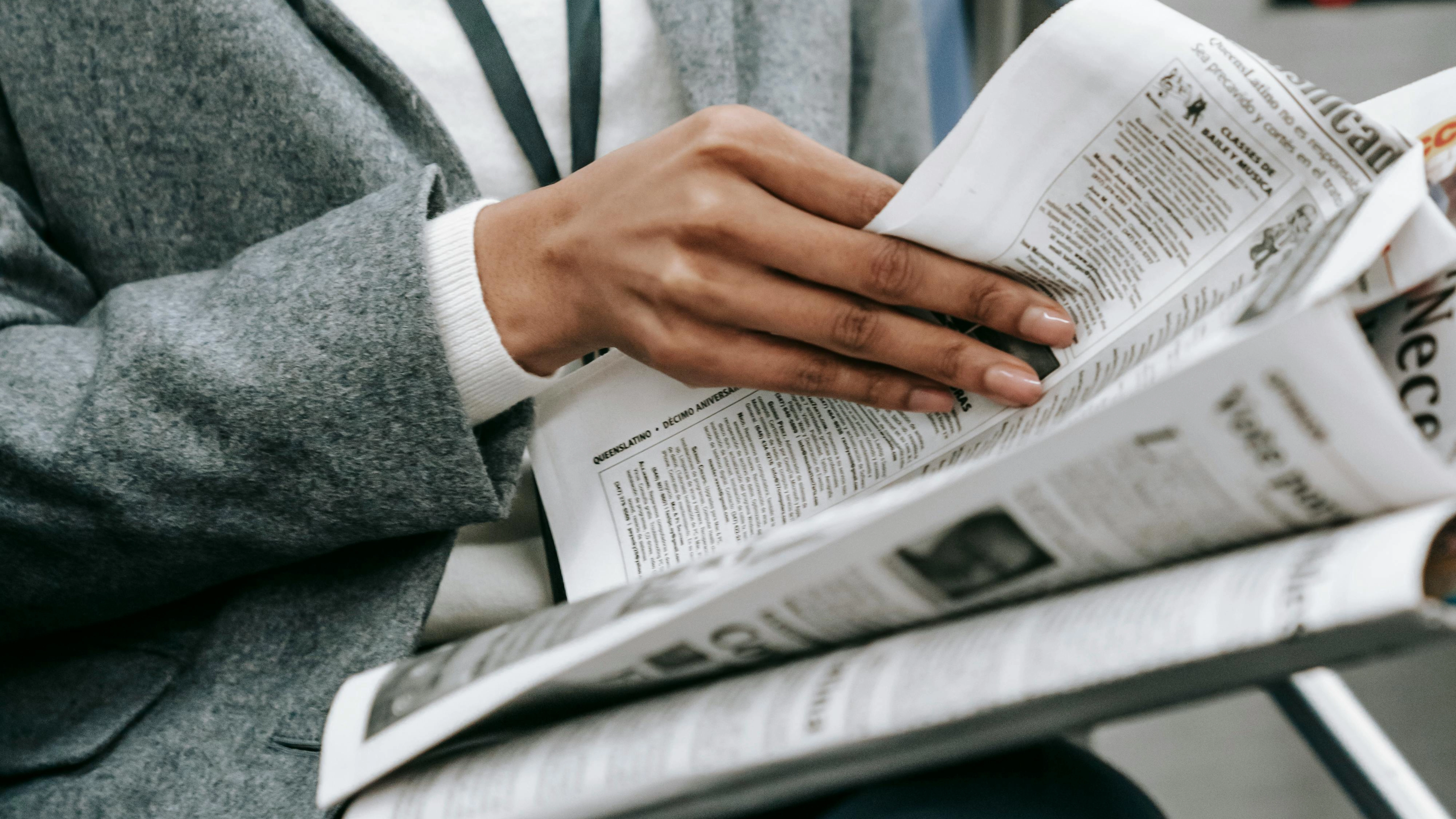 Un inconnu en costume gris lit le journal dans un train.